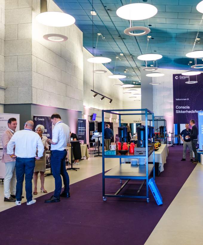 Deltagere besøger udstillingsstande i et lyst foyerområde under en faglig konference.