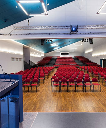 Stor konferencesal på Sjælland i Roskilde Kongres- og Idrætscenter Konferencesal i Roskilde Kongres- og Idrætscenter på Sjælland med scene, podie og stoleopsætning til flere hundrede deltagere.