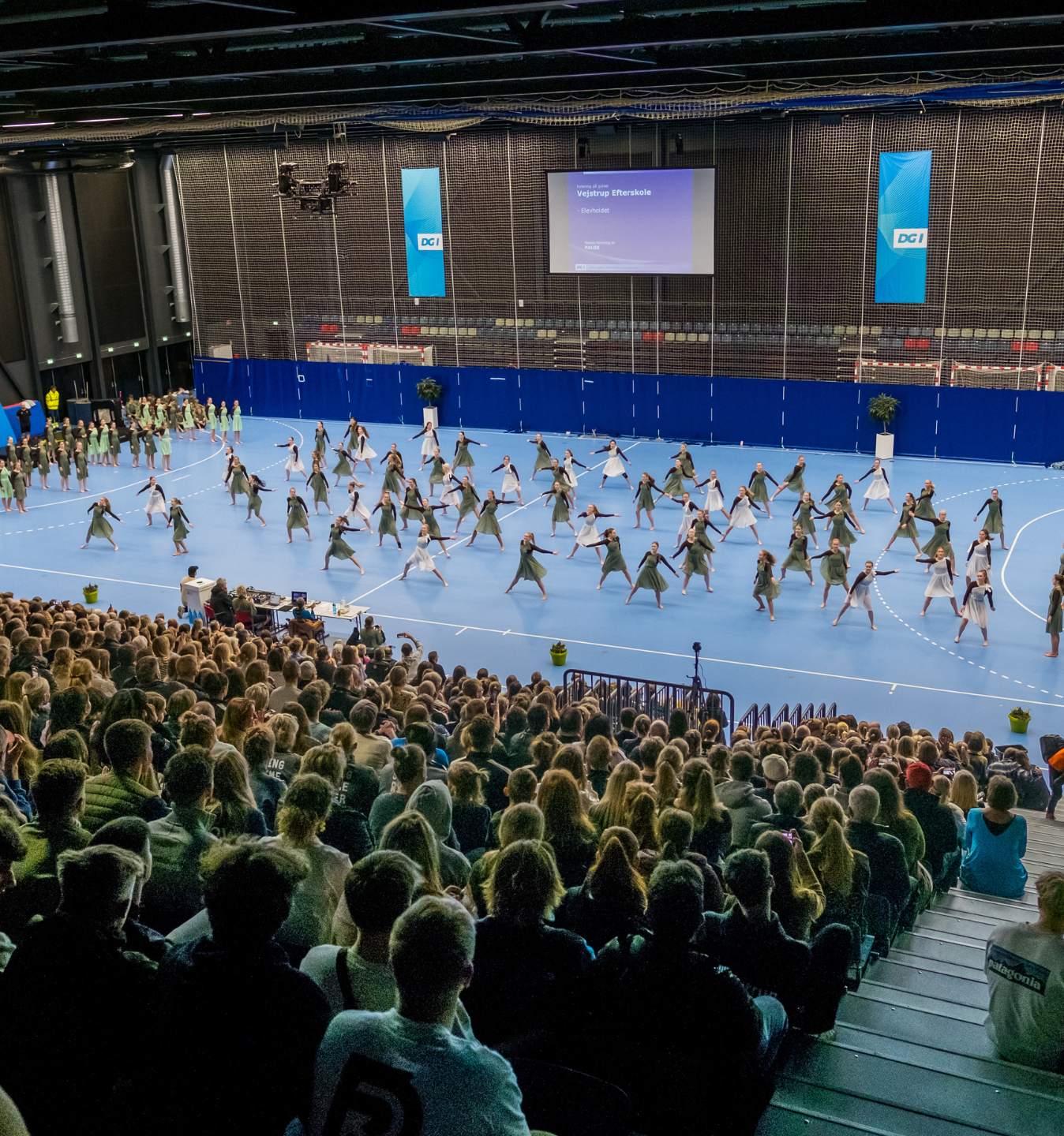 Gymnastikopvisning i en stor sportshal med publikum på tribunen