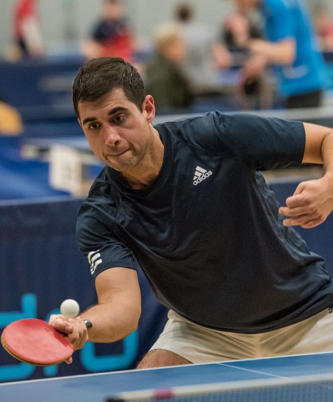 Bordtennisspiller rækker efter bolden under en kamp ved Bordtennisfestival 2025 i Roskilde Kongres- og Idrætscenter.