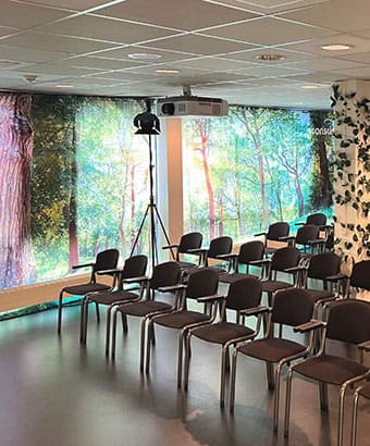 Konferencefaciliteter på Sjælland i Roskilde Kongres- og Idrætscenter Mødelokale i Roskilde Kongres- og Idrætscenter på Sjælland med stoleopsætning, projektorer og grønne detaljer, klar til konference eller seminar.