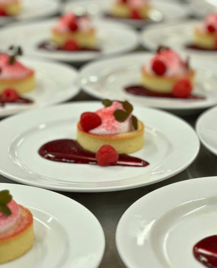 Små desserter med hindbær anrettet på tallerkener