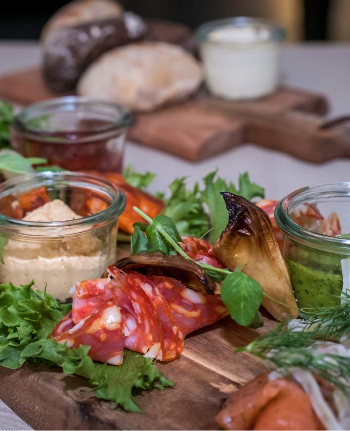 Anretning med salat, charcuteri, brød og små glas med tilbehør