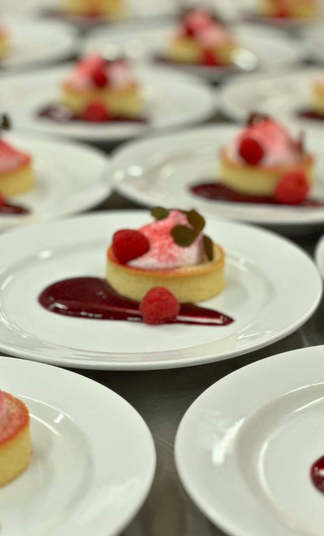 Små desserter med hindbær anrettet på tallerkener