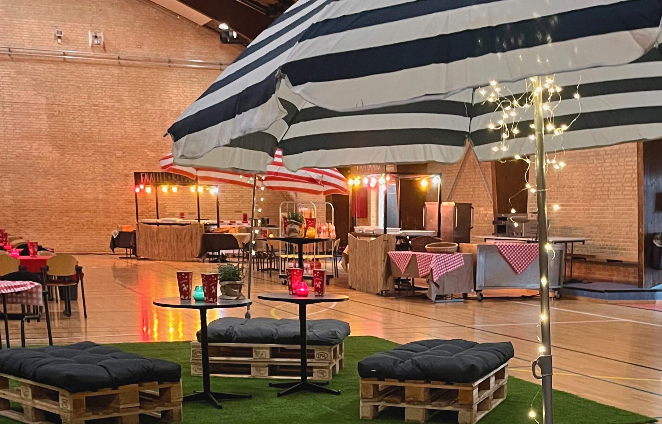 Hyggeligt loungeområde med parasoller, lyskæder og street food boder, klar til firma sommerfest i Roskilde Kongres- og Idrætscenter.