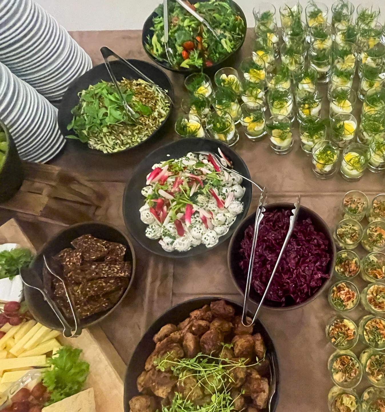 Økologisk messeforplejning Buffet med økologiske retter, herunder salater, grøntsager, brød, ost og små portionsanretninger, serveret som en del af messeforplejningen.