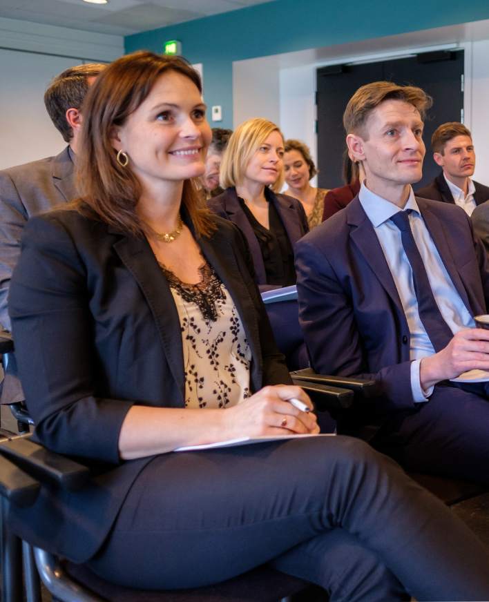 Deltagere lytter til et oplæg i et mødelokale.