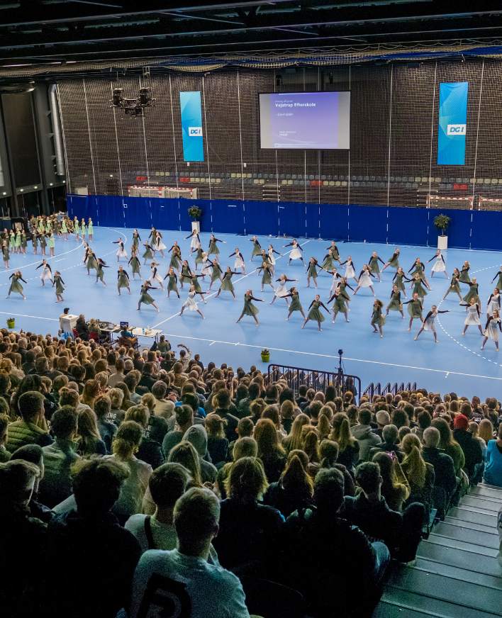Gymnastikopvisning i en stor sportshal med publikum på tribunen