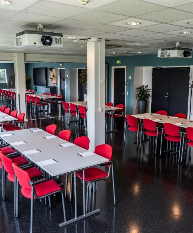 Maglekilde indrettet med borde og røde stole i en fleksibel opstilling til møder, workshops og undervisning. 