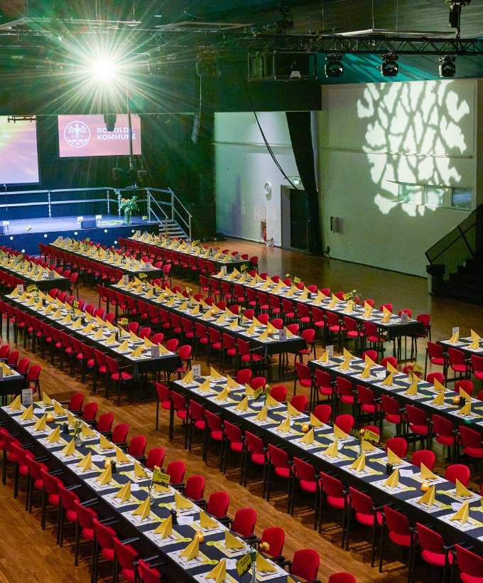 Festlig event med langborde og scenelys i sal A.