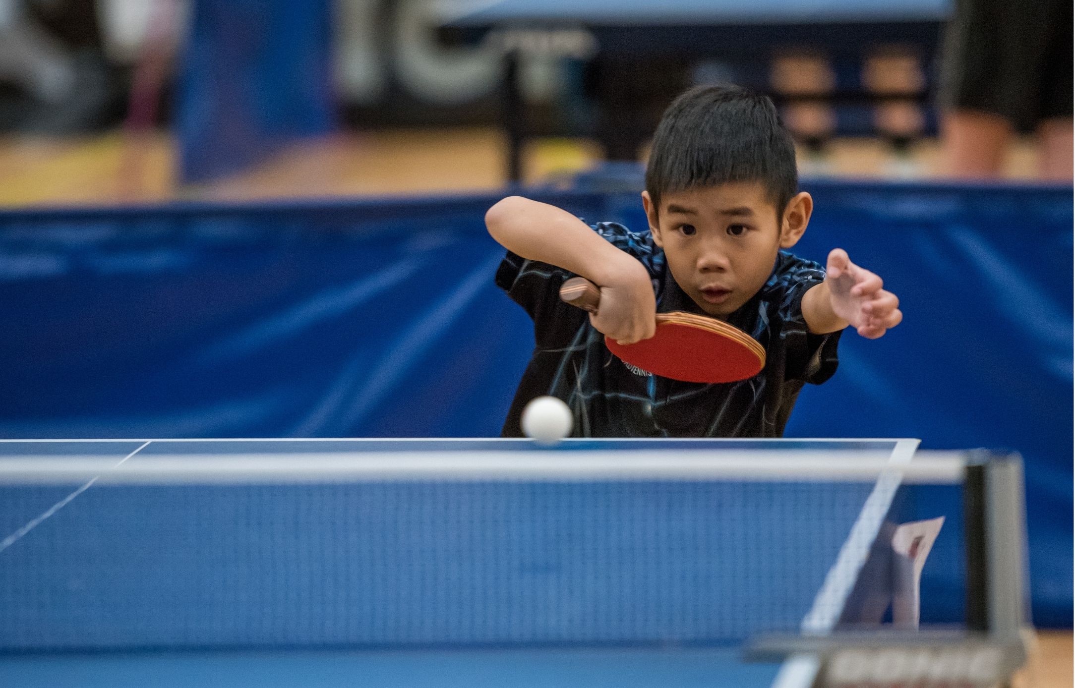 Ung bordtennisspiller koncentrerer sig om bolden under Bordtennisfestival 2025 i Roskilde Kongres- og Idrætscenter.
