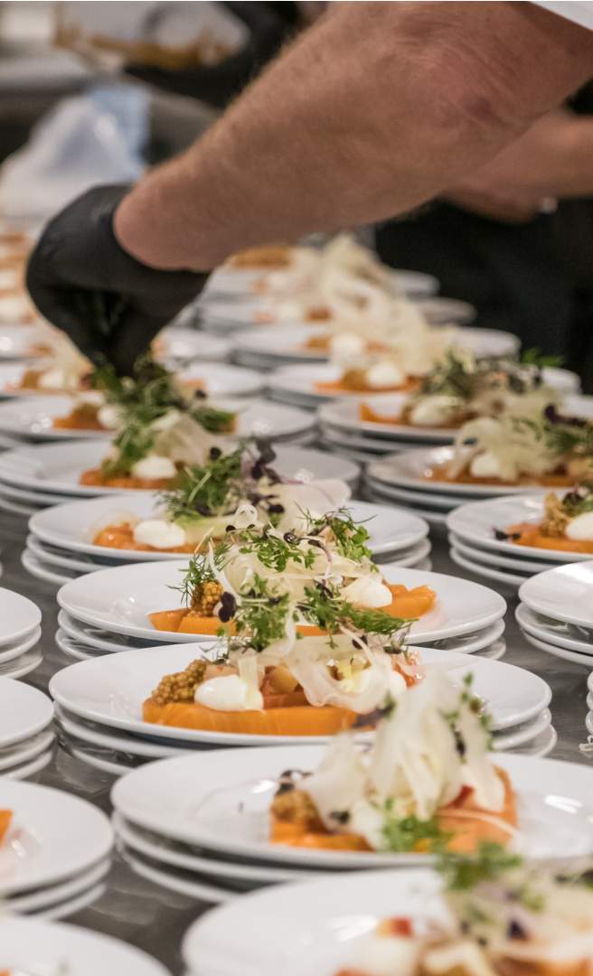 Tallerkener med forret anrettes med friske urter til konferencemiddag.