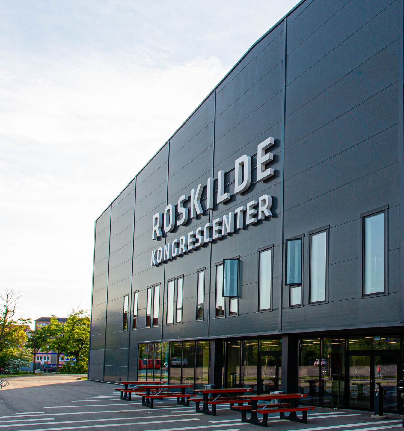Facade ved Roskilde Kongres- og Idrætscenter med indgangsparti og husets skiltning. Billedet viser bygningens ydre og de fysiske rammer omkring huset.