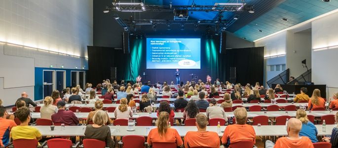Sal A1 i Roskilde Kongres- og Idrætscenter indrettet med skolebordsopstilling, scene og storskærm til konferencer, møder og faglige arrangementer. 
