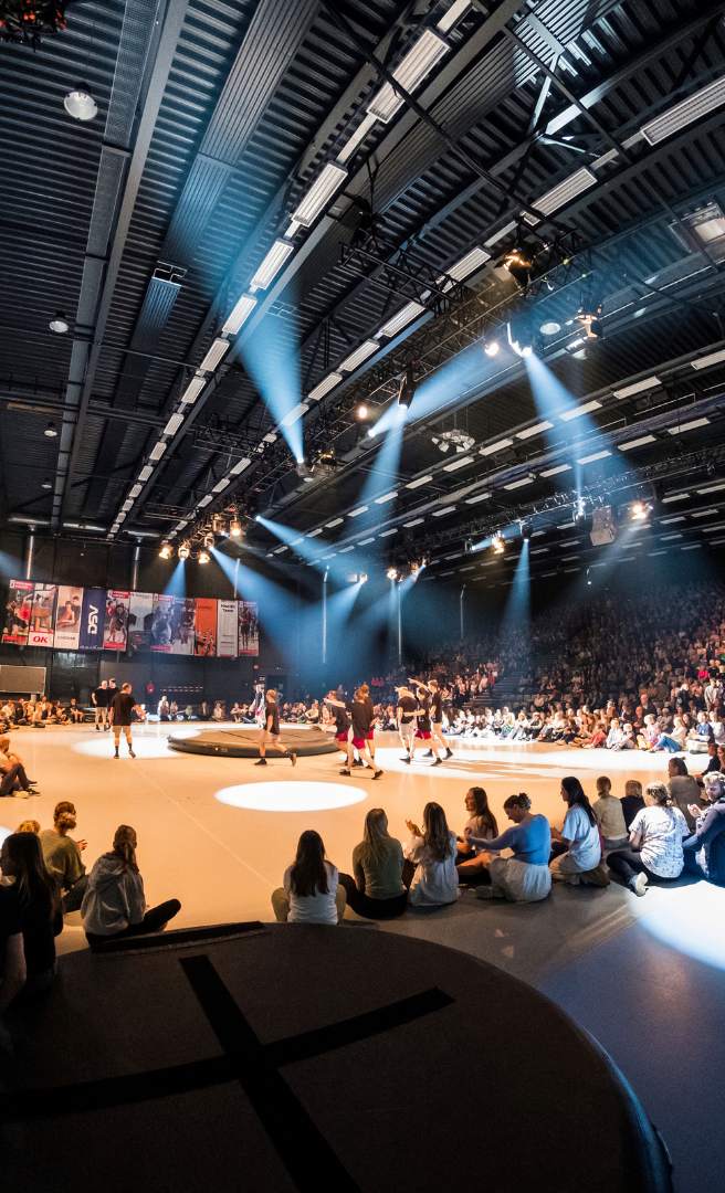 Sportsopvisning i en stor hal med scenelys og publikum