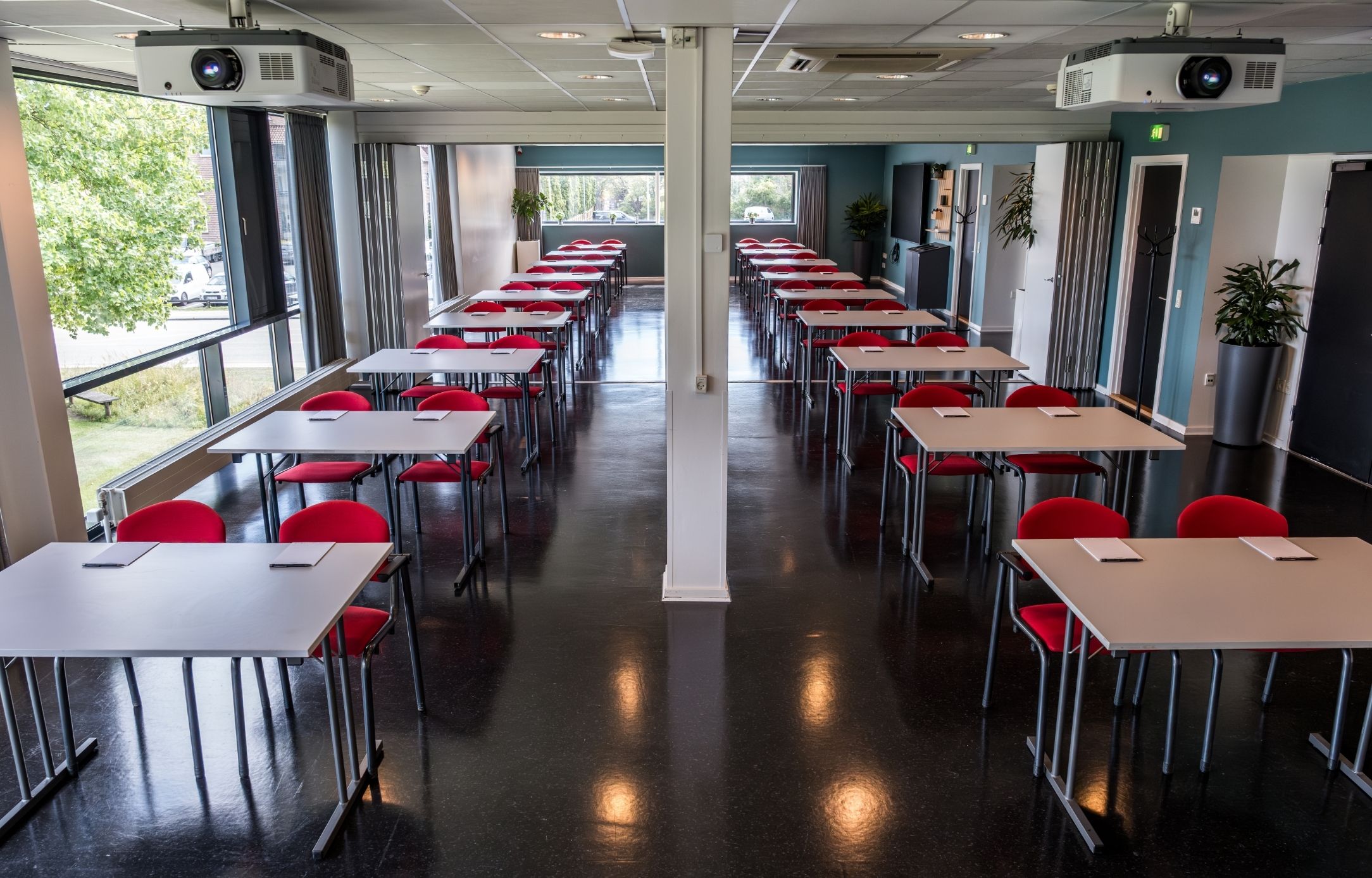 Maglekilde indrettet med borde og røde stole i skolebordsopstilling med god plads til deltagere og oplæg.