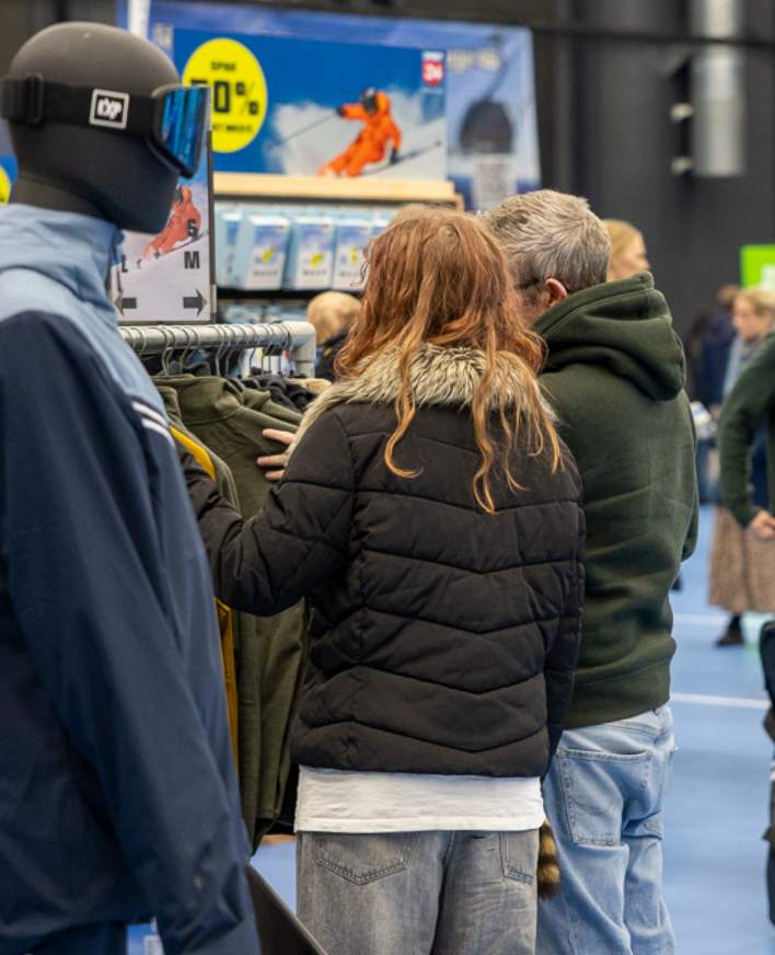 Besøgende ser på tøj ved en stand på en skioutlet messe.