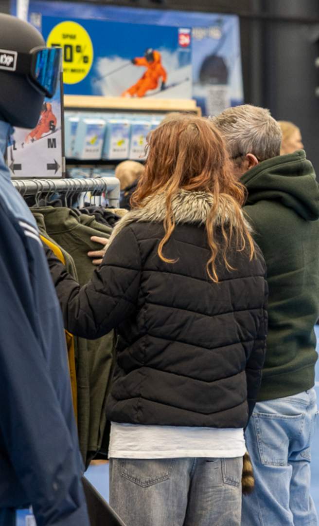 Besøgende ser på tøj ved en stand på en skioutlet messe.