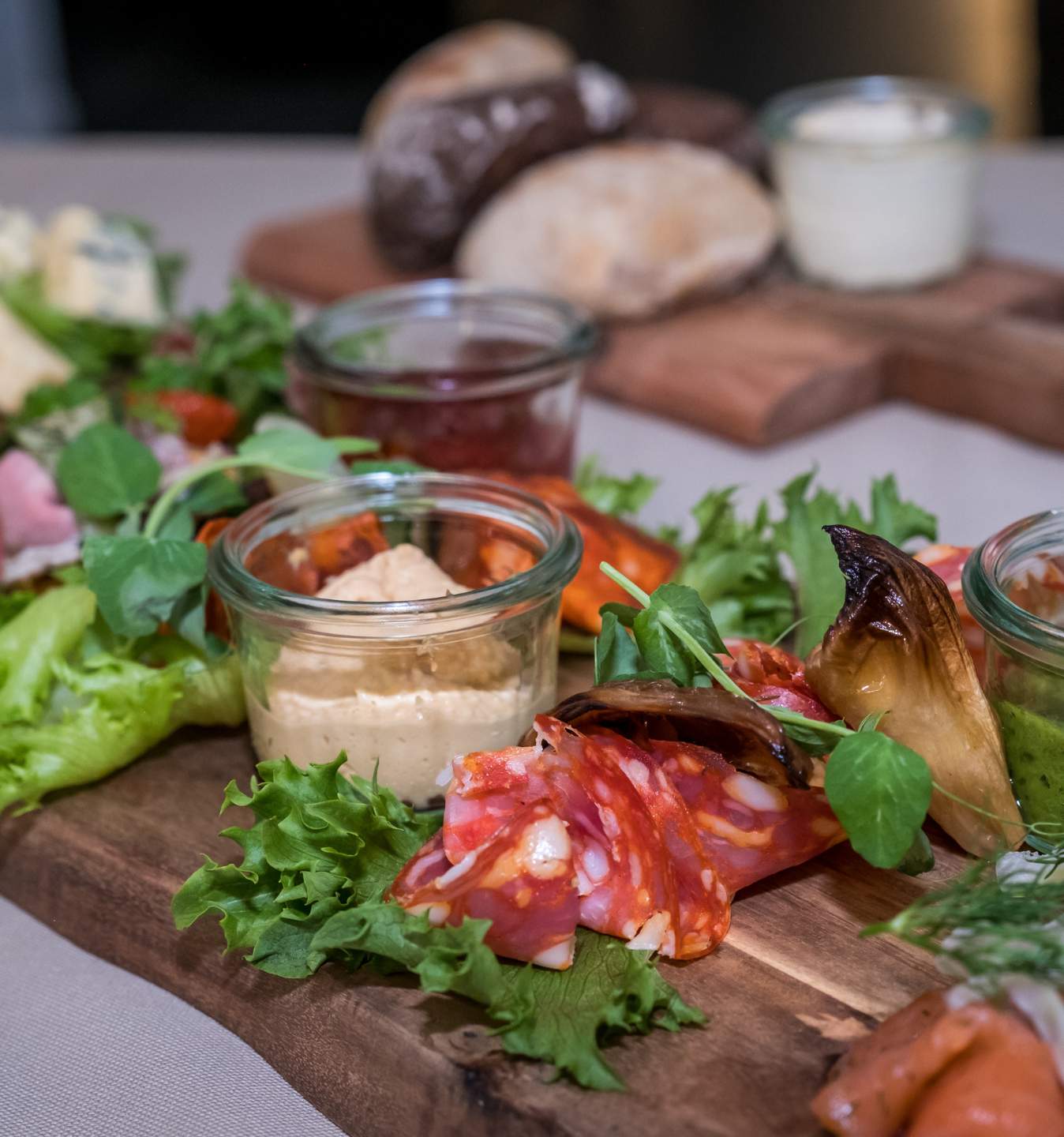 Anretning med salat, charcuteri, brød og små glas med tilbehør