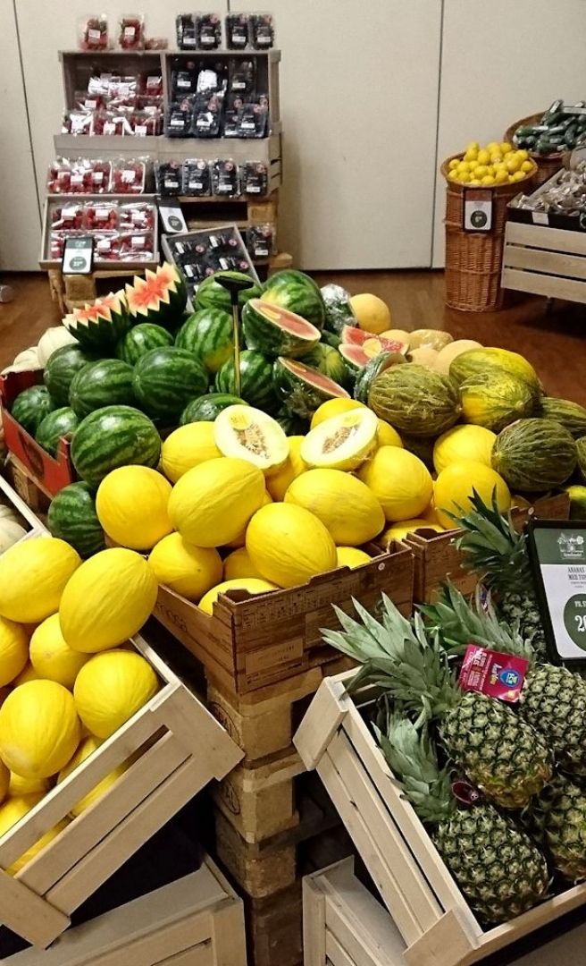 Frugtudstilling på messe i Roskilde Kongrescenter Udstilling med vandmeloner, meloner, ananas og bær præsenteret i trækasser på en messe i Roskilde Kongrescenter.