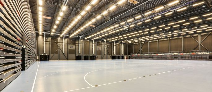 Hal D i Roskilde Kongres- og idrætscenter med stort sportsareal, banemarkeringer, højt til loftet og indbyggede tribuner langs hallens sider. 