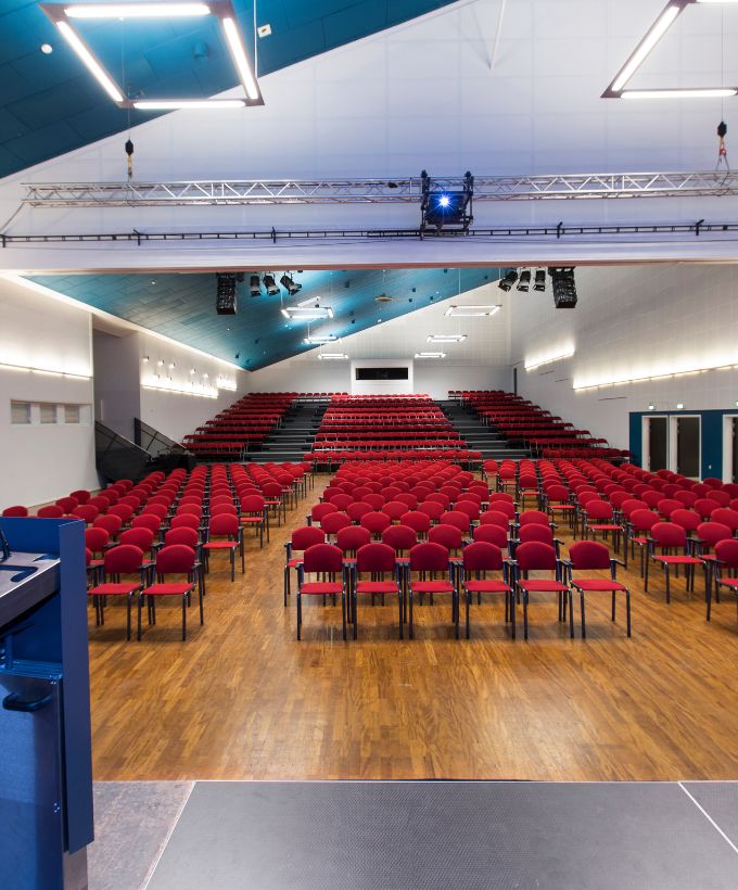 Sal A i Roskilde Kongres- og Idrætscenter med biografopstilling, scene og teleskoptribune klar til konference, foredrag eller større arrangement.