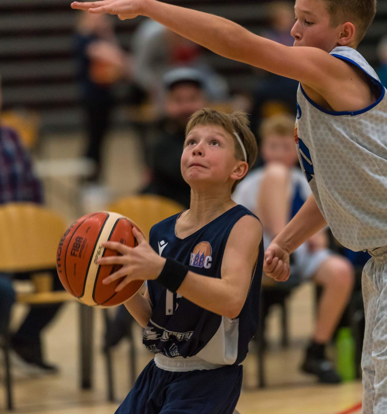 Ung basketballspiller med bolden mellem to modspillere under en kamp