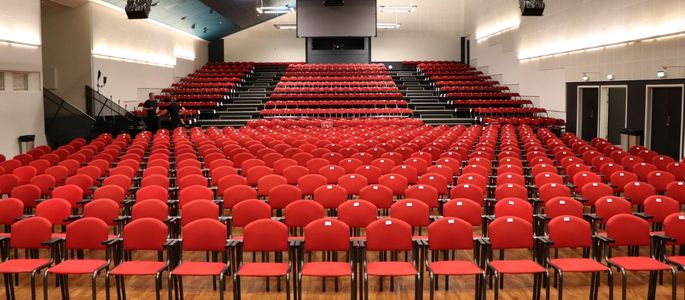 Sal A i Roskilde Kongres- og Idrætscenter indrettet med røde stole i biografopstilling og tribunepladser til større konferencer og arrangementer. 
