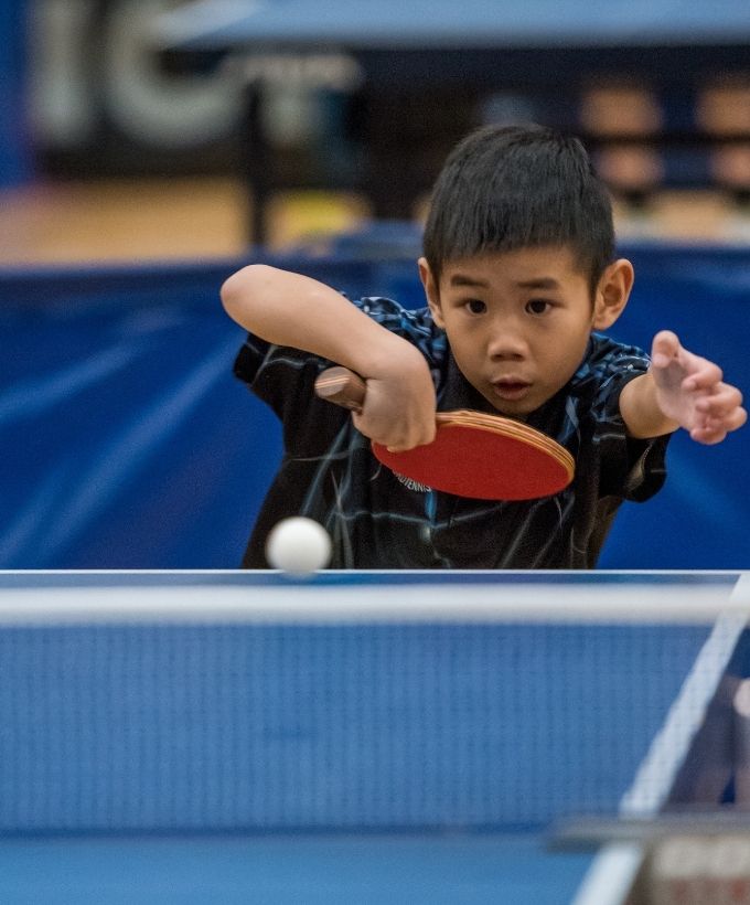 Ung bordtennisspiller koncentrerer sig om bolden under Bordtennisfestival 2025 i Roskilde Kongres- og Idrætscenter.