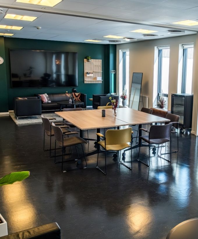 Lovise indrettet med stort mødebord og et uformelt loungeområde med sofaer og lænestole.