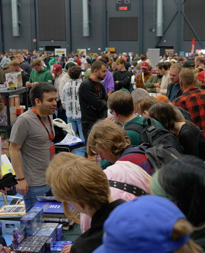 Mange besøgende samlet ved stande på en travl messe.
