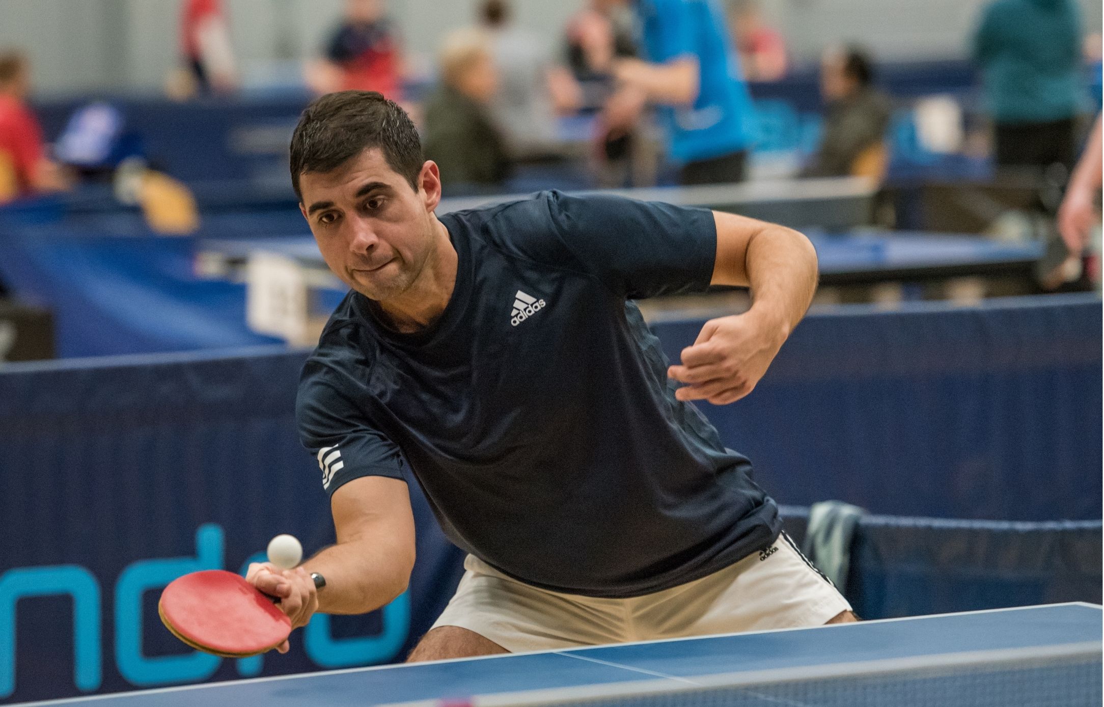 Bordtennisspiller rækker efter bolden under en kamp ved Bordtennisfestival 2025 i Roskilde Kongres- og Idrætscenter.