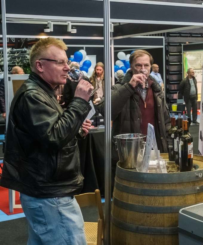 Vinstand med smagsprøver på messe i Roskilde Kongres- og Idrætscenter Besøgende nyder vinsmagning ved en udstillingsstand på messe i Roskilde Kongres- og Idrætscenter, hvor lokale og internationale produkter præsenteres.