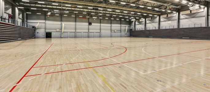 Hal C i Roskilde Kongres- og Idrætscenter med stort sportsareal, trægulv med banemarkeringer og indbyggede tribuner til idræt og større arrangementer. 