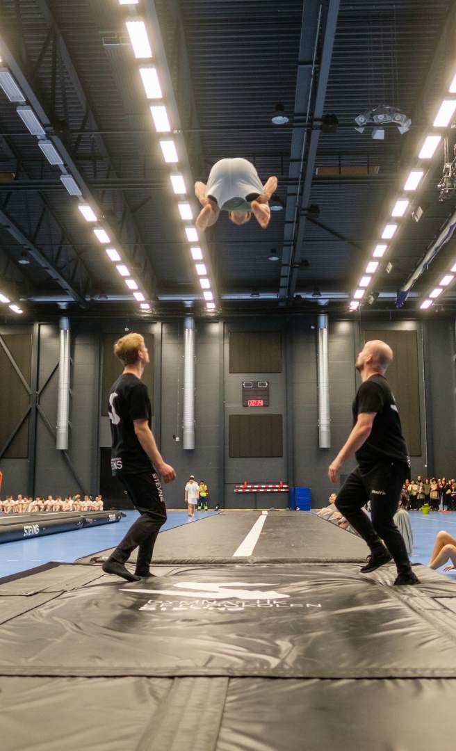 Gymnast udfører et spring på en airtrack i en sportshal