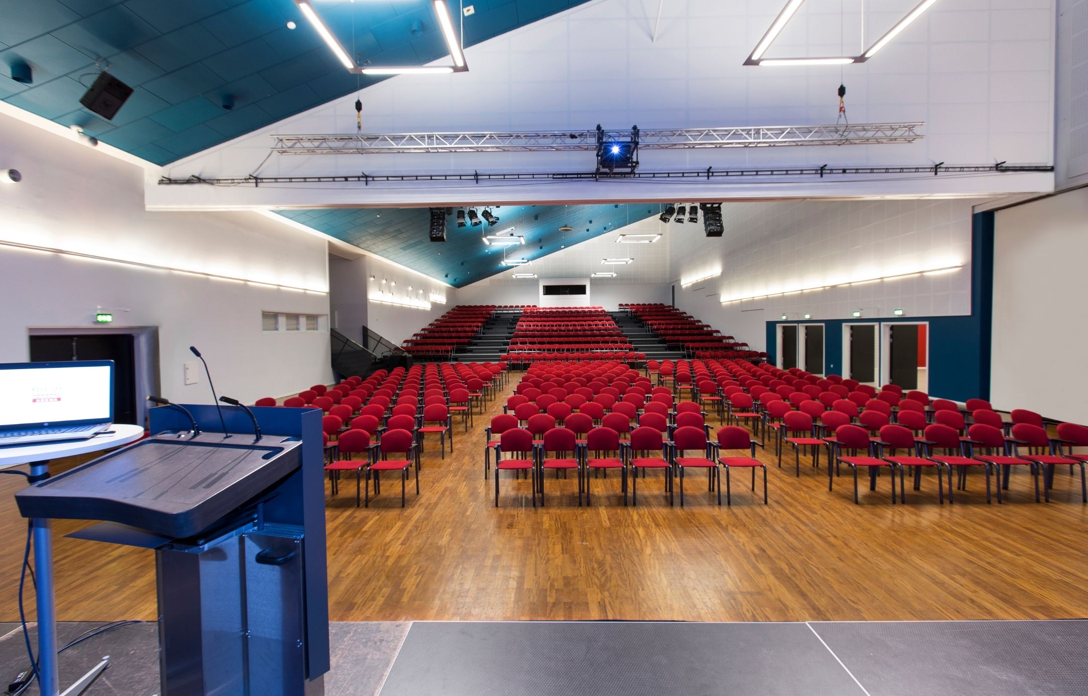 Stor konferencesal på Sjælland i Roskilde Kongres- og Idrætscenter Konferencesal i Roskilde Kongres- og Idrætscenter på Sjælland med scene, podie og stoleopsætning til flere hundrede deltagere.
