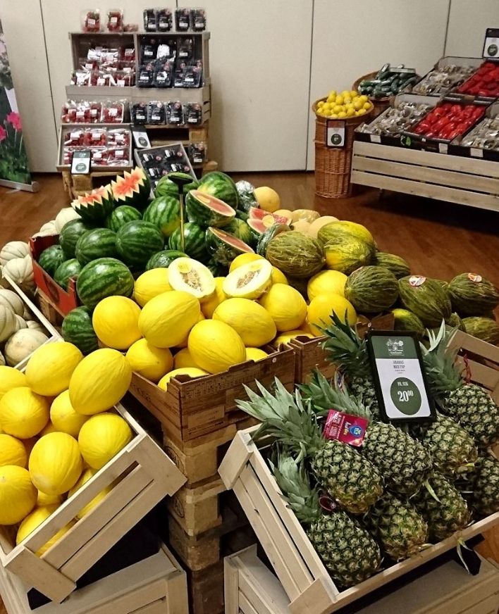 Frugtudstilling på messe i Roskilde Kongrescenter Udstilling med vandmeloner, meloner, ananas og bær præsenteret i trækasser på en messe i Roskilde Kongrescenter.
