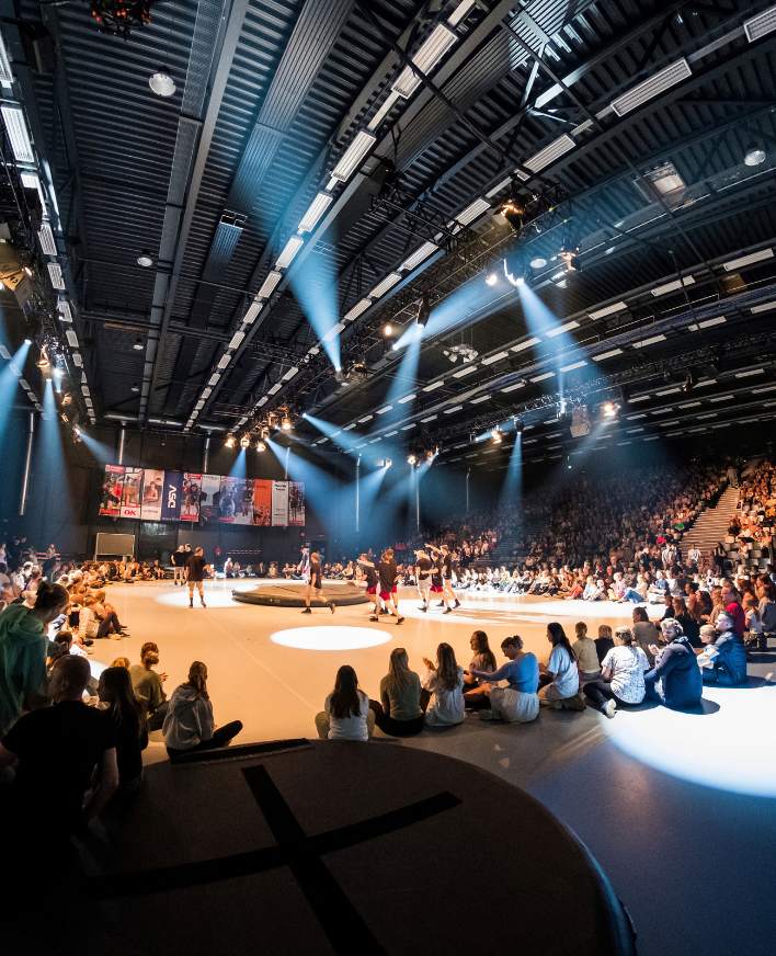 Sportsopvisning i en stor hal med scenelys og publikum